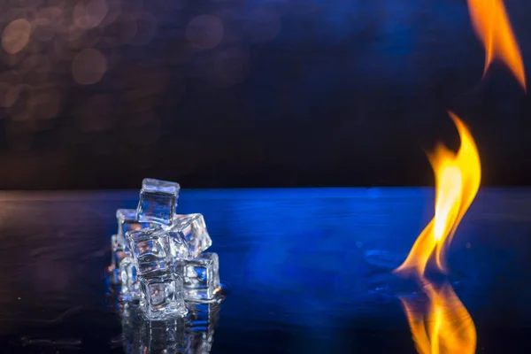 Cubes of ice and fire on a water surface on an abstract background — Stock Photo, Image