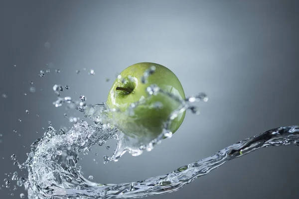 Manzana verde y salpicadura de agua sobre fondo gris —  Fotos de Stock