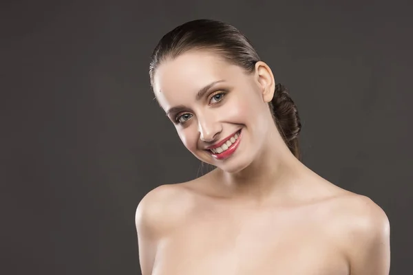 La hermosa chica desnuda hombros sonríe sobre un fondo gris — Foto de Stock
