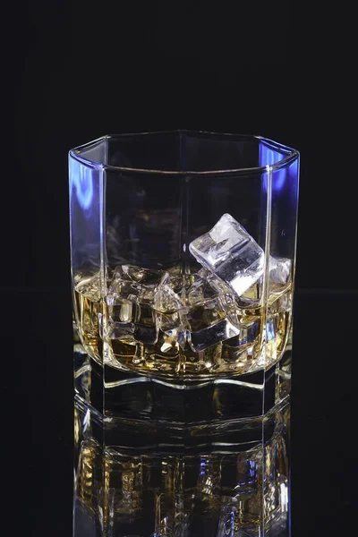 Glas whisky med is på en svart bakgrund och blå lighrt — Stockfoto