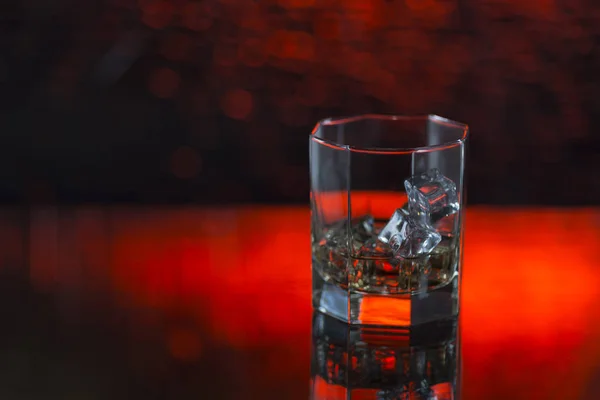 Glas Whisky mit Eis auf rotem Hintergrund — Stockfoto