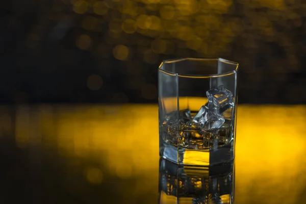 Bicchiere di whisky con ghiaccio su fondo giallo — Foto Stock