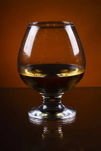 Cognac-Glas auf orangefarbenem Hintergrund — Stockfoto