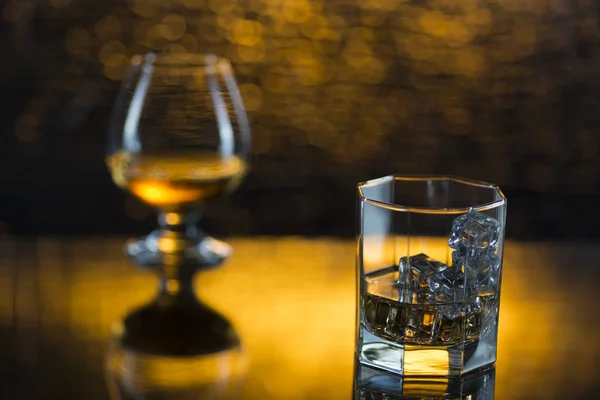 Cam o viski buz ve bardağı konyak sarı bokeh arka plan üzerinde — Stok fotoğraf