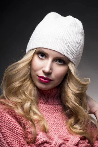 The girl in a pink sweater and a white cap on a gray background — Stock Photo, Image