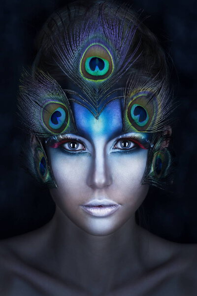 the girl's portrait with a vanguard make-up and feathers of a pe