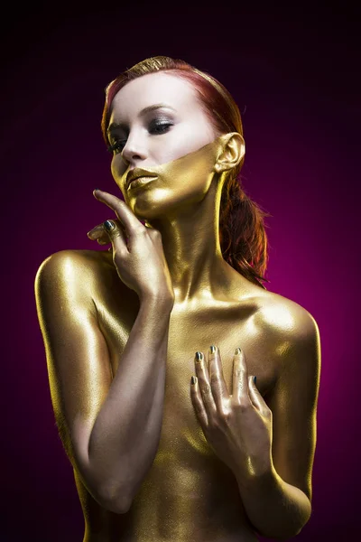 La chica teñida de oro sobre un fondo violeta — Foto de Stock