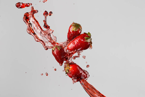four strawberries and red juice splash