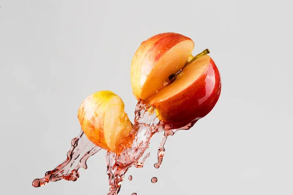 Salpicadura de manzana y jugo rojo aislado sobre un fondo gris — Foto de Stock