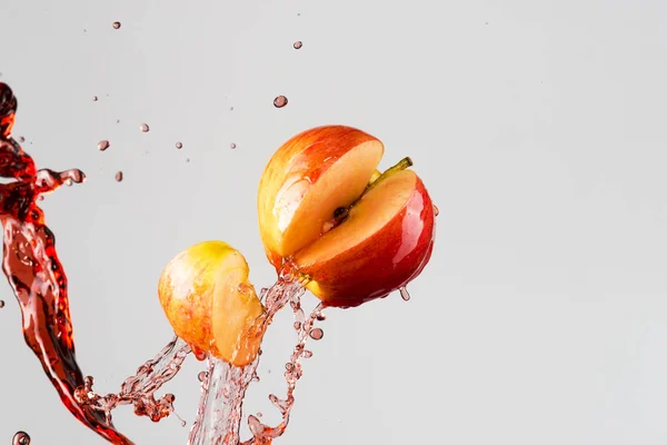 Salpicadura de manzana y jugo rojo aislado sobre un fondo gris —  Fotos de Stock