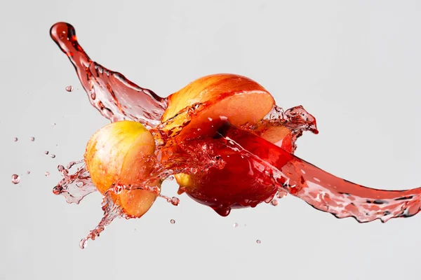 Salpicadura de manzana y jugo rojo aislado sobre un fondo gris —  Fotos de Stock