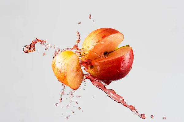 Apfel- und Rotsaft spritzt isoliert auf grauem Hintergrund — Stockfoto