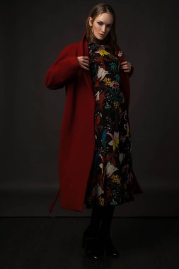 gri bir arka plan üzerinde kırmızı paltolu şık kız modeli