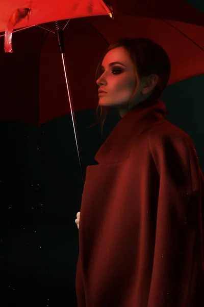 the girl  in a red coat with a red umbrella in the rain