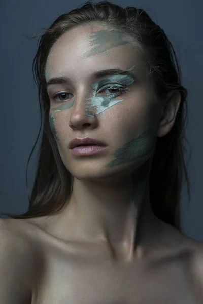 Porträt eines schönen Mädchens mit einer blauen Maske aus Ton auf dem Gesicht — Stockfoto