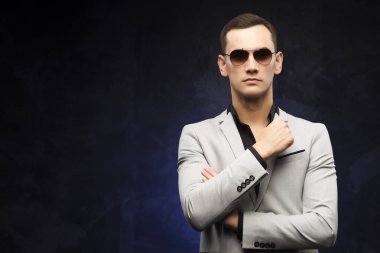 adam gri bir takım ve mavi bir arka plan üzerinde güneş gözlüğü.