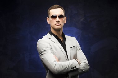 adam gri bir takım ve mavi bir arka plan üzerinde güneş gözlüğü.