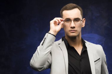 adam gri bir takım ve mavi bir arka plan üzerinde gözlük.