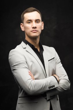 Karanlık bir arka plan üzerinde gri elbiseli genç adam.