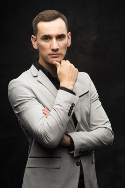Karanlık bir arka plan üzerinde gri elbiseli genç adam.