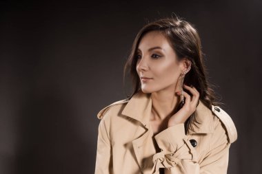 Gri bir arka plan üzerinde yağmurluk esmer kız