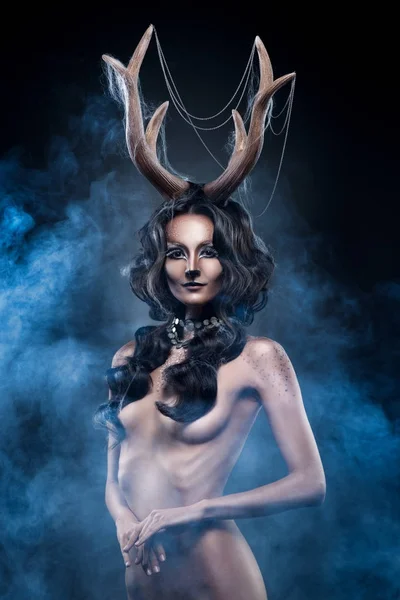 The naked beautiful girl with antlers on her head and a deer mak Stock Picture