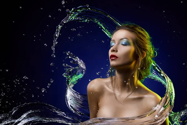 Vacker flicka täckt med vattenstänk på en blå bakgrund — Stockfoto