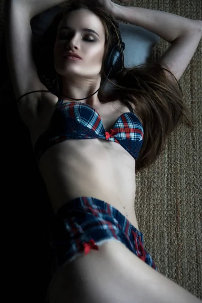 A bela garota deitada em um chão vestindo roupas íntimas e uma jea — Fotografia de Stock