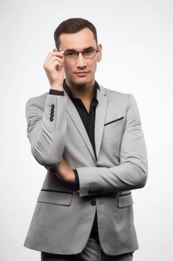 Gri bir takım ve gözlük genç bir adam onun glas düzeltiyor