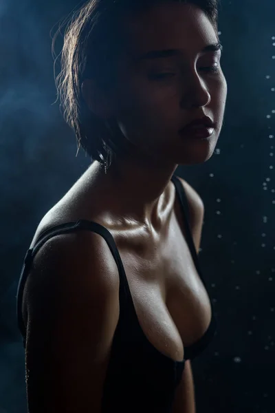 Szép nedves nagy mellű lány visel a fekete fürdőruha a sötét — Stock Fotó