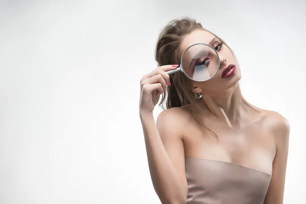 Beautiful naked shoulders girl looking through a magnifying glas — Stock Photo, Image