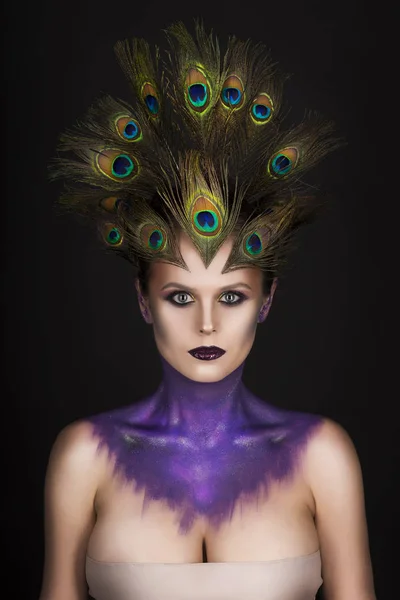 Beautiful big breast girl wearing peacock feathers in her hair and artistic violet shiny body art on her neck, vanguard makeup — Stock Photo, Image