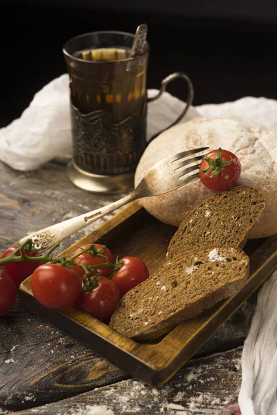 Natura morta concettuale di pane a fette, pomodorini, bicchiere di — Foto Stock