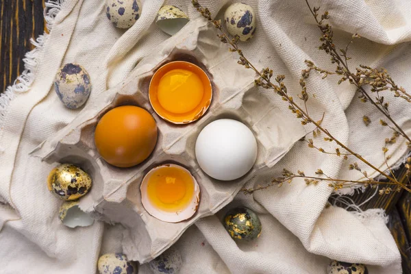 Yolks of broken egg in eggshell in carton egg box and quail eggs