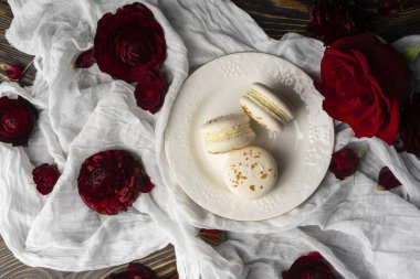 Gül bloss tarafından çevrili bir plaka üzerinde yalan üç bademli kurabiye pasta