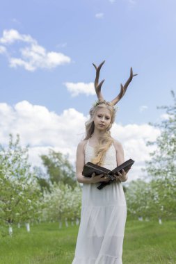 Teen beautiful blonde girl wearing white dress with deer horns o clipart