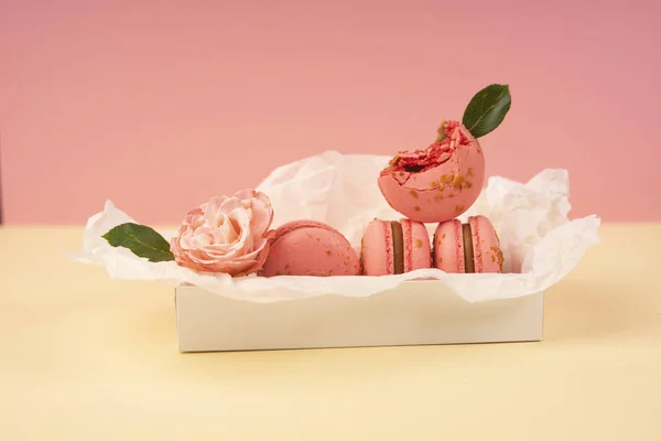 Verschillende roze bitterkoekjes taarten waarvan er één is gebeten en versieren — Stockfoto