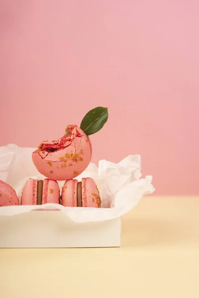 Verschillende roze bitterkoekjes taarten waarvan er één is gebeten en versieren — Stockfoto