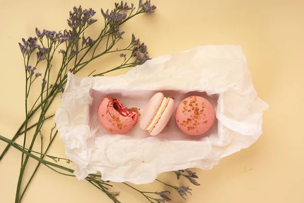 Verschillende roze bitterkoekjes taarten waarvan er één in een gift is gebeten bo — Stockfoto