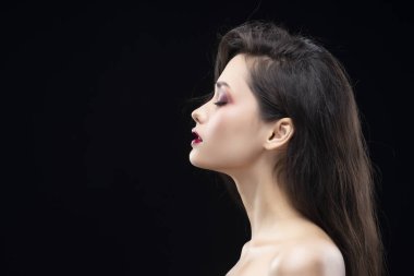 Bir güzel göz alıcı esmer kız yan portresi. Parıldayan makyaj, kırmızı dudaklar. Sağlıklı pürüzsüz bir cilt. Siyah izole. Uzay kopyalayın. Ticari ve reklam tasarım.