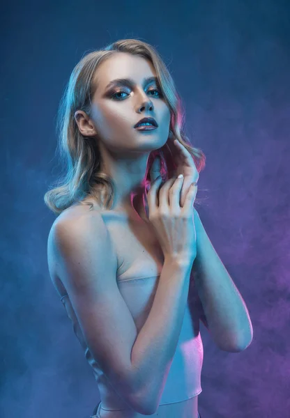Vacker blond ung flicka med trendig makeup vidrör hennes ansikte — Stockfoto