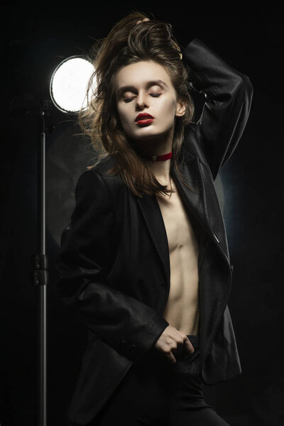 Beautiful braless girl with red lips, wearing an unbuttoned blac