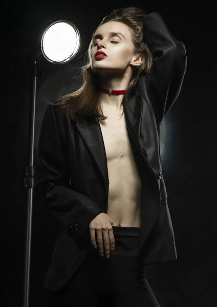 Beautiful braless girl with red lips, wearing an unbuttoned blac — Stock Photo, Image