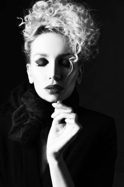 Zarif bir saç stili ve geniş göğüsleri olan, sütyen, eşarp ve ceket giyen güzel sarışın bir kız karanlıkta saçlarına dokunuyor. Moda, ticari tek renkli kara film tasarımı. Kapat.