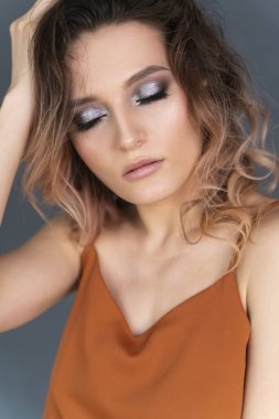 Gri bir duvara karşı poz veren modaya uygun bir elbise giyen güzel bir kız. Moda, reklam ve ticari tasarım. Portreyi kapat