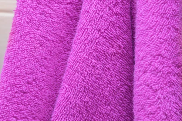 Wavy dry bath towels of color purple hanging in bathroom close-u