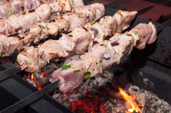 Едва ли жареное маринованное мясо на металлических шашлыках над углями — стоковое фото