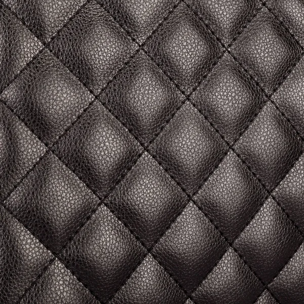 A piece of monochrome black leather stitched in the form of rhombuses with beautiful highlights — Stock Photo, Image