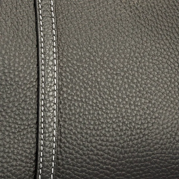 Texture black leather with one neat stitch sewn with white thread closeup — Stock Photo, Image