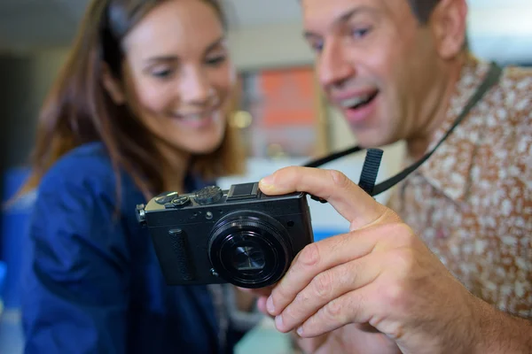 Homme et femme regardant l'affichage de l'appareil photo numérique — Photo